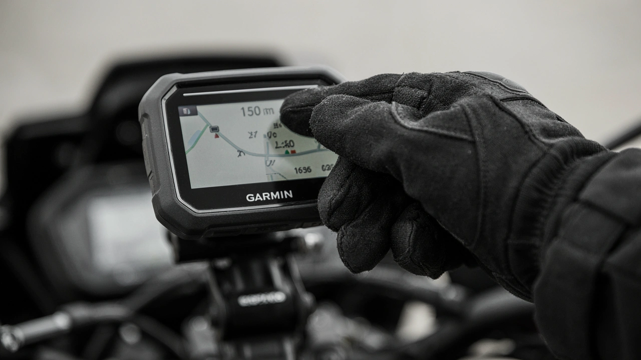 Main gantée touchant l'écran d'un GPS Garmin zūmo XT3