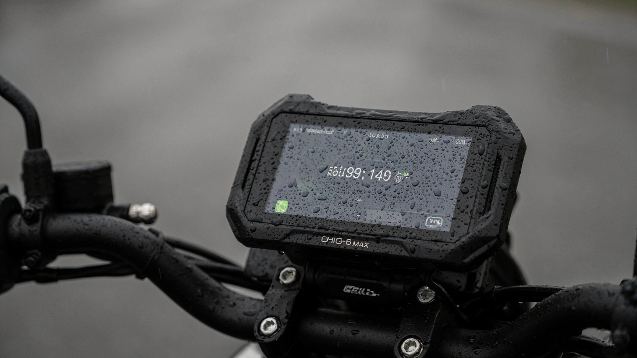 Écran Chigee AIO-6 Max couvert de gouttes de pluie sur le guidon, toujours allumé